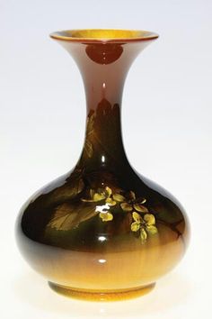 a brown and yellow vase sitting on top of a white table