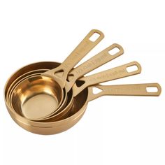 four gold measuring cups with spoons in them