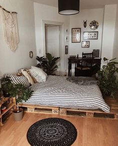 a bedroom with a bed made out of wooden pallets and plants on the floor