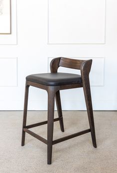 a wooden chair sitting on top of a carpeted floor next to a white wall