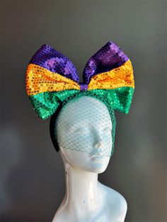 Celebrate the vibrant spirit of Mardi Gras with the Mardi Gras Bow Fascinator. This lively headpiece features a large, sequined bow in the iconic colors of purple, gold, and green, complemented by a delicate net veil. Perfect for Mardi Gras celebrations, themed parties, or any festive event, the Mardi Gras Bow Fascinator adds a playful and colorful touch to your ensemble. Age Group/Gender - Kids and Women Size/Type - One size fits all adults Color - Purple, Orange and Green Material - Sequin Acc