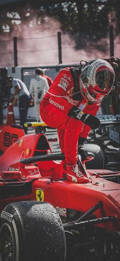 a man standing on top of a red race car