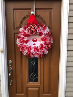 a red and white wreath on the front door of a house with an elf hat