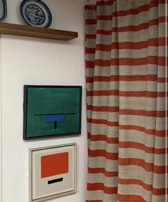 two paintings on the wall next to a red and white striped curtain in a bathroom