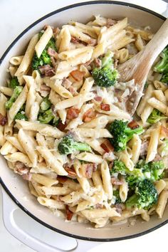 a bowl filled with pasta and broccoli on top of a white countertop