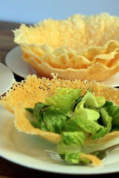 a plate topped with lettuce next to a bowl filled with cheese and chips