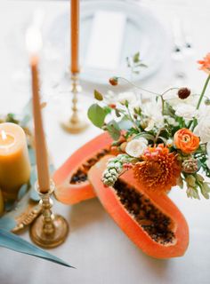 an arrangement of flowers and candles on a table