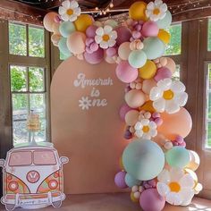 an arch made out of balloons with flowers on the front and back, along with a vw bus