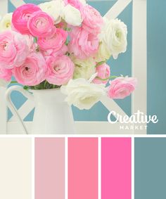 a white vase filled with pink and white flowers next to a blue wall in the background