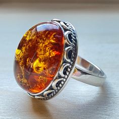 "* Materials: Baltic Amber,925 Sterling Silver * Stone color: Cognac * Stone size: 0.7\"X 0.55\"(17.5 mm x 14 mm) * Weight: 8 gram * Available in sizes 6-8.5 * This ring is for adults only. Huge Natural Baltic Cognac Amber Ring . Sterling Silver Ring. Did you know that Amber was one of the first materials ever used for accessorizing? Ornaments made out of amber were found on prehistoric people dating all the way back to the Stone Age, which was over 10,000 years ago! Throughout centuries it has Prehistoric People, Amber Earrings, Amber Ring, Natural Amber, Stone Age, Gift For Woman, Clothes Closet, Amber Jewelry, Creative Jewelry