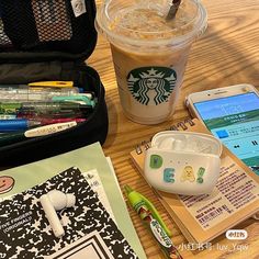 a cup of coffee, cell phone and other items on a wooden table next to a bag