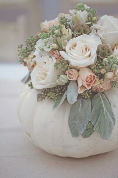 a white pumpkin decorated with flowers and greenery