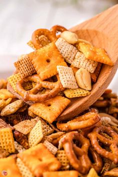 a wooden spoon filled with cheetos and pretzel snack mix in a bowl