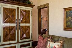 a living room filled with furniture next to a painting on the wall and an armoire