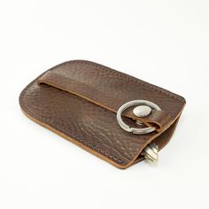 a brown leather wallet with a metal ring on it