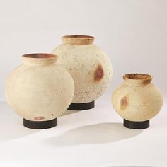 three white vases sitting next to each other on a table