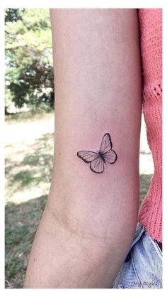 a small butterfly tattoo on the left inner arm, with an outline of a butterfly