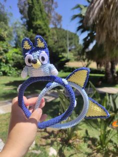 a hand holding a crocheted toy in the shape of a fish with eyes