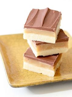 three pieces of chocolate and peanut butter bars stacked on top of each other in a yellow plate