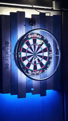 a dart board mounted to the side of a wooden wall with neon lights on it