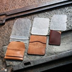 three different colors of leather sitting on top of a stone slab next to a tool