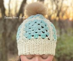 a woman wearing a crocheted hat with a pom - pom