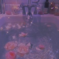 pink roses are floating in a bathtub with soapy water and sparkles on the floor