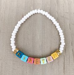 Name Bracelet 🤍📿 Simple, chic Name bracelet, looks cute with any attire!  Made with 0/6 white seed beads, gold accents and colored square letters that read your name or word of your choice (colors of letters may vary) *Please put name in Personalization Section* CARING TIPS FOR YOUR JEWELRY ⭐️Treat and store with care. ⭐️ For longevity, avoid exposing your jewelry to water. ⭐️ Avoid having direct contact with lotions, perfumes, sanitizers as these chemicals may cause discoloration of your jewelry. White Name Bracelet With 8mm Beads As Gift, White Tiny Beads Stretch Bracelet For Friendship, White Stretch Bracelet With Tiny Beads For Friendship, White Beaded Name Bracelet For Gifts, White Charm Bracelet With 8mm Beads As Gift, White Name Bracelet With Letter Beads, White Stretch Bracelet With Letter Beads As Gift, Adjustable White Beaded Name Bracelet, Personalized White Round Beads Bracelet