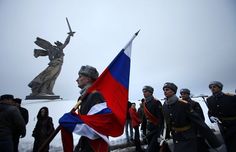 a group of people standing in front of a statue with a russian flag on it