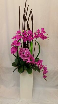 a white vase filled with purple flowers on top of a table