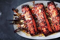 grilled fish and vegetables on a white plate with brown sauce drizzled over them