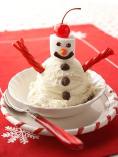 a small snowman sitting in a white bowl on top of a red table cloth