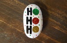 a painted rock with the word ho ho on it sitting on top of a wooden table