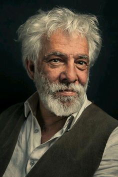 an older man with white hair wearing a vest