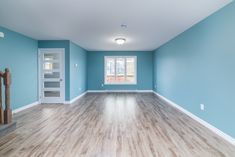 an empty room with blue walls and wood floors