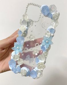 a hand holding an iphone case with flowers and pearls