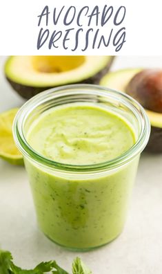 an avocado dip in a glass jar with cilantro on the side