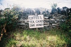 a sign in front of a stone wall that says coffee's tea cakes jam honey