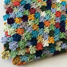 a multicolored crocheted blanket on a white surface