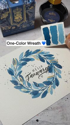 the ink is being used to create this watercolor wreath with blue and gold accents