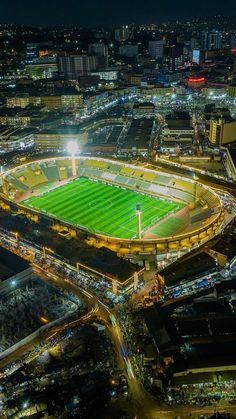 an aerial view of a soccer stadium at night with the lights on and green grass