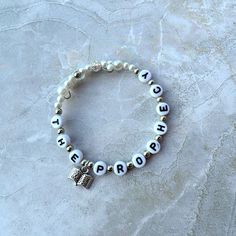 a white beaded bracelet with the words,'keep progress'written on it