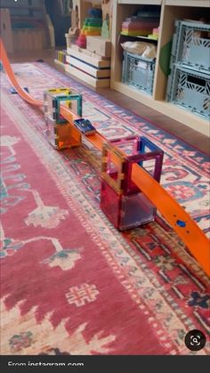 a toy train is on the floor next to a rug