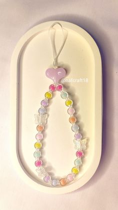 a white tray with a necklace on it and a pink heart hanging from the front