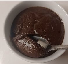 a white bowl filled with chocolate pudding and a spoon