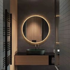 a bathroom with a round mirror above the sink and lights on the wall behind it