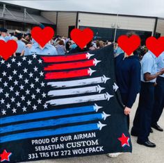 a group of people standing next to each other holding a flag with hearts on it