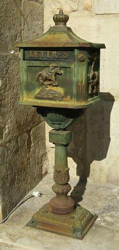 an old fashioned mail box sitting on the ground