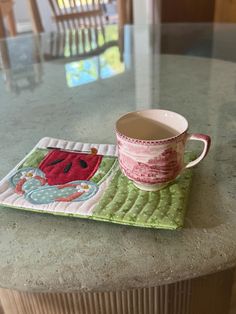 a cup and saucer sitting on top of a green place mat next to a wooden chair