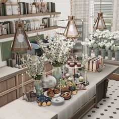 a table topped with lots of vases filled with flowers next to shelves full of books